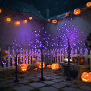 Halloween ghost trees with lights adorned with purple lights and surrounded by carved pumpkins in a spooky garden.